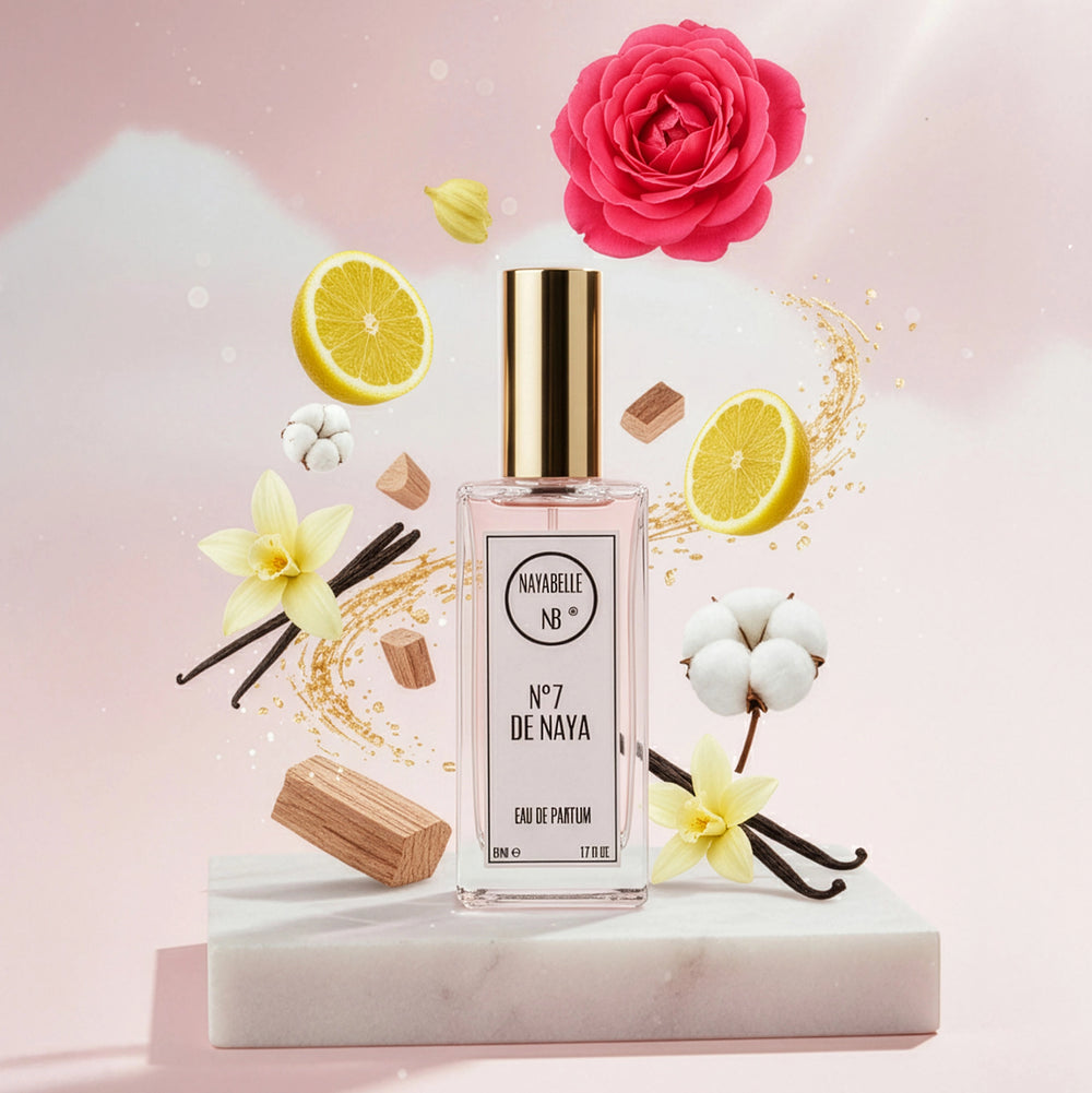 Parfum N° 7 de Naya par Nayabelle. Flacon posé sur un socle de marbre blanc, entouré des ingrédients de la fragrance flottant dans les airs : rose, citron, vanille, fleur de coton et morceaux de bois. Photo créative pour e-commerce.