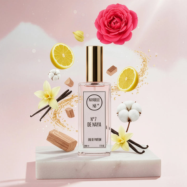 Parfum N° 7 de Naya par Nayabelle. Flacon posé sur un socle de marbre blanc, entouré des ingrédients de la fragrance flottant dans les airs : rose, citron, vanille, fleur de coton et morceaux de bois. Photo créative pour e-commerce.