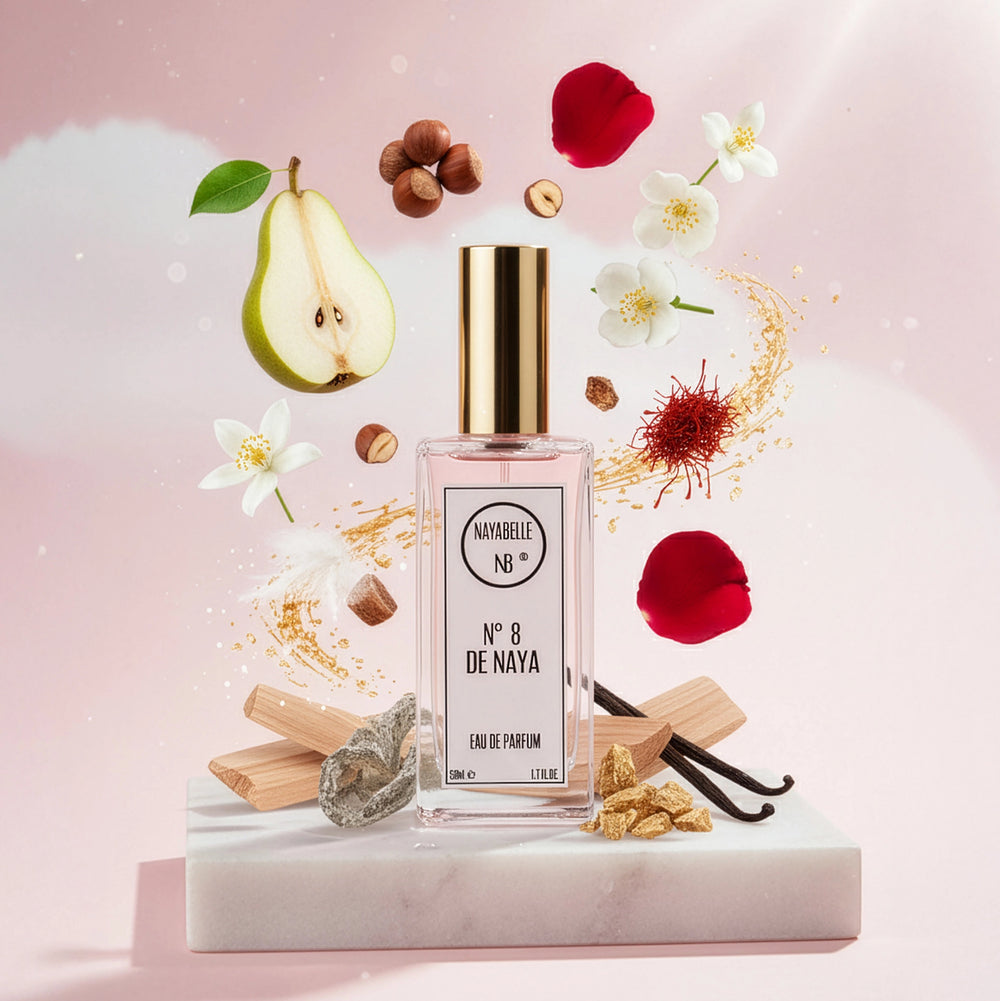 Parfum N° 8 de Naya par Nayabelle. Flacon posé sur un bloc de marbre, entouré des ingrédients de la fragrance flottant dans les airs : poire, noisettes, jasmin, safran et vanille. Photo créative pour e-commerce.