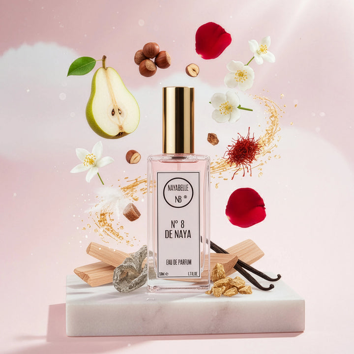 Parfum N° 8 de Naya par Nayabelle. Flacon posé sur un bloc de marbre, entouré des ingrédients de la fragrance flottant dans les airs : poire, noisettes, jasmin, safran et vanille. Photo créative pour e-commerce.